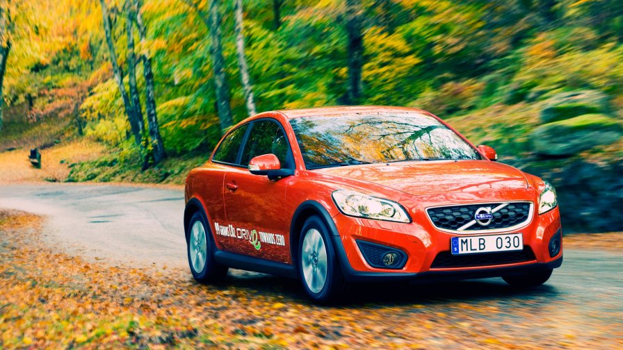 Beautiful Red Volvo in the Autumn Yellow Forest on the Road