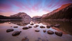 Stones in Lake and Purple Sunset in Mountain Valley